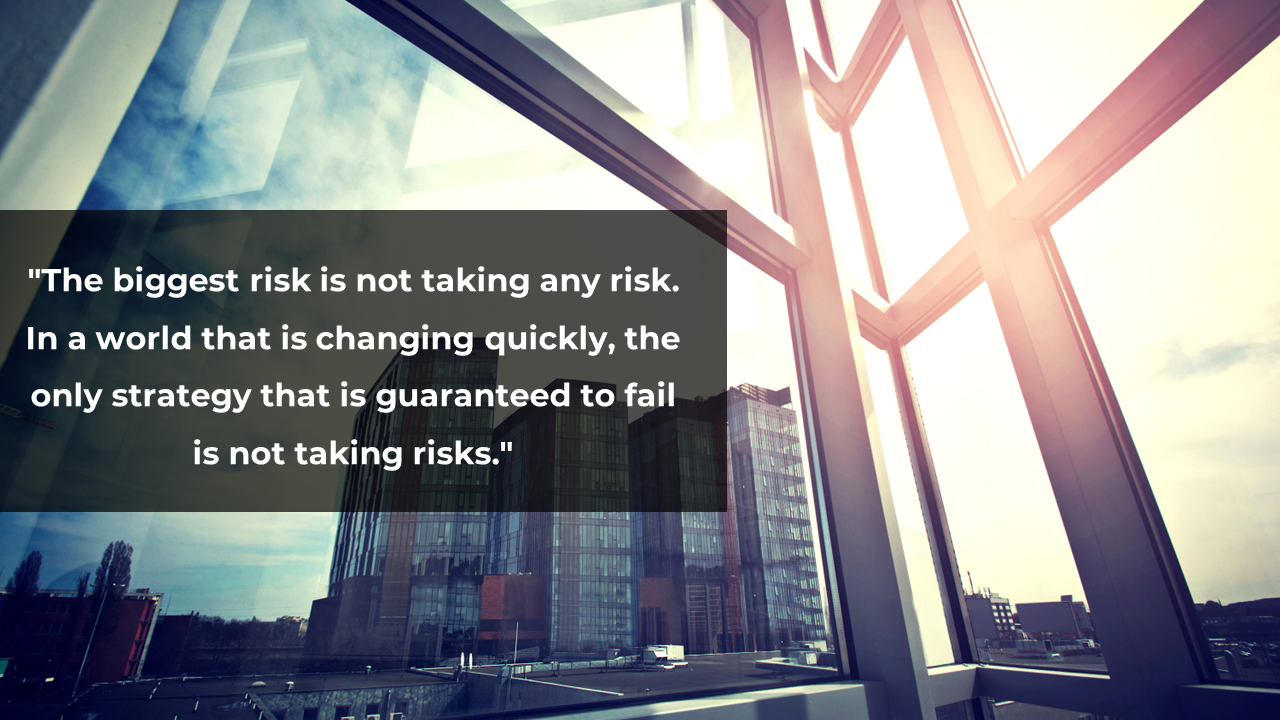 City skyline views through a glass window with a quote emphasizing the importance of taking risks.