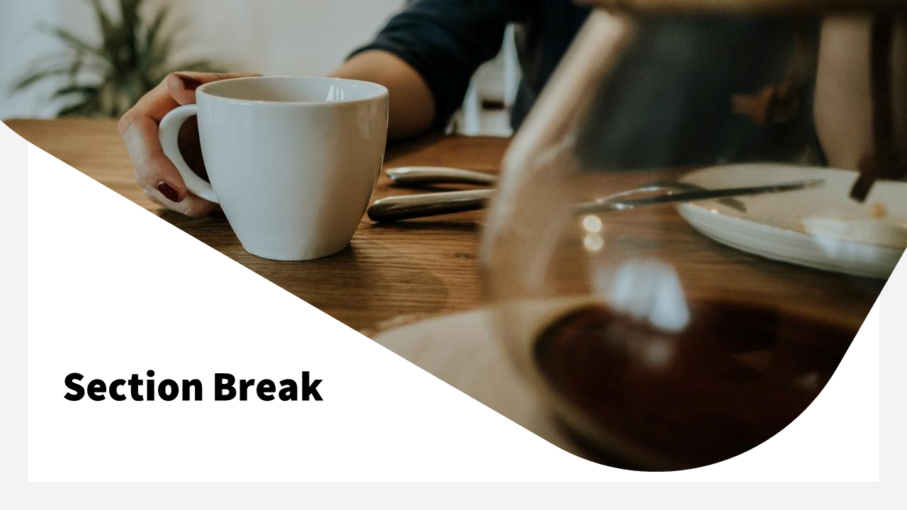 A hand holding a white cup of coffee on a wooden table with a plate and cutlery in the background indicates a section break.