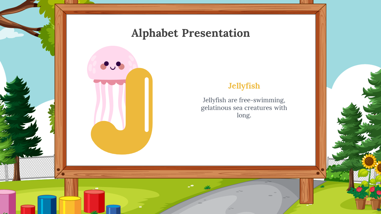 Yellow J with a pink cartoon jellyfish beside it, placed on a wooden framed whiteboard, outdoor park with trees and blocks.