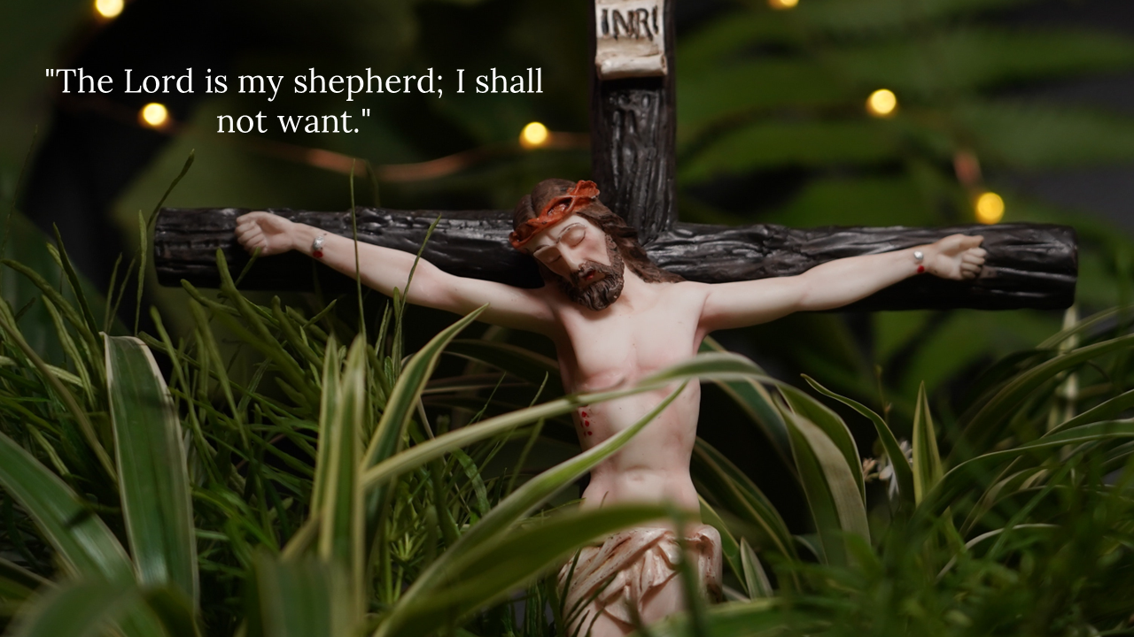 Figurine of Jesus on a wooden cross among green foliage, with string lights in the background and a Bible verse overlay.