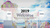 Decorative welcome event slide with flower arrangements on pedestals, ocean view, and placeholders for date.