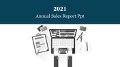 2021 Annual Sales Report PowerPoint slide featuring a workspace with a laptop, clipboard, and design tools.