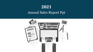 2021 Annual Sales Report PowerPoint slide featuring a workspace with a laptop, clipboard, and design tools.