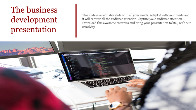 A professional working on a laptop displaying code, with a monitor showing mountain scenery in the background.
